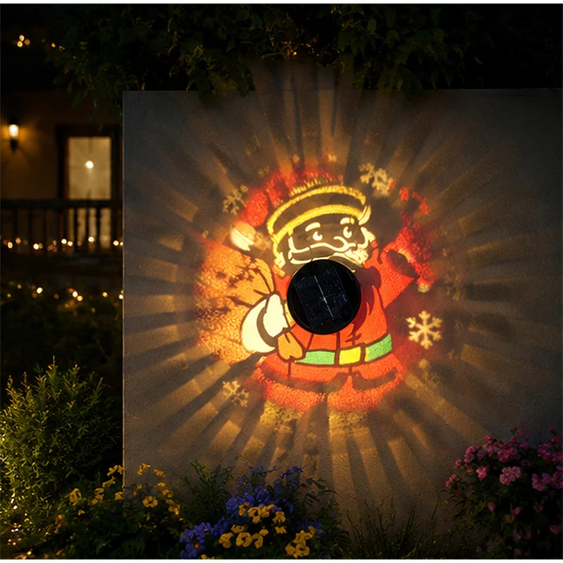 Solar Santa Projection Light with its top solar panel visible beside colorful patterns on a garden wall