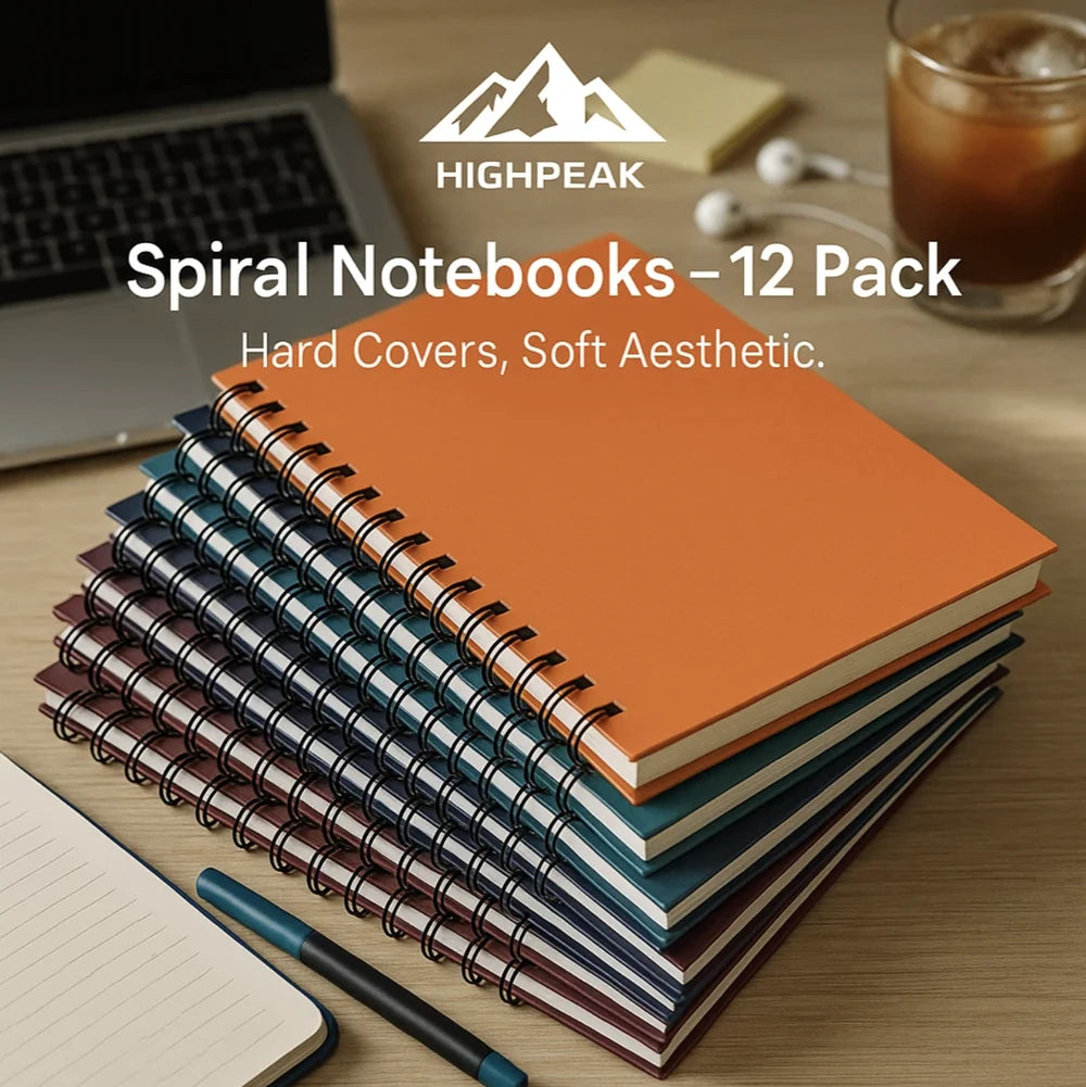 HighPeak Spiral Notebooks – 12 Pack with hardcover thick paper in jewel tones stacked on desk with laptop and pen.