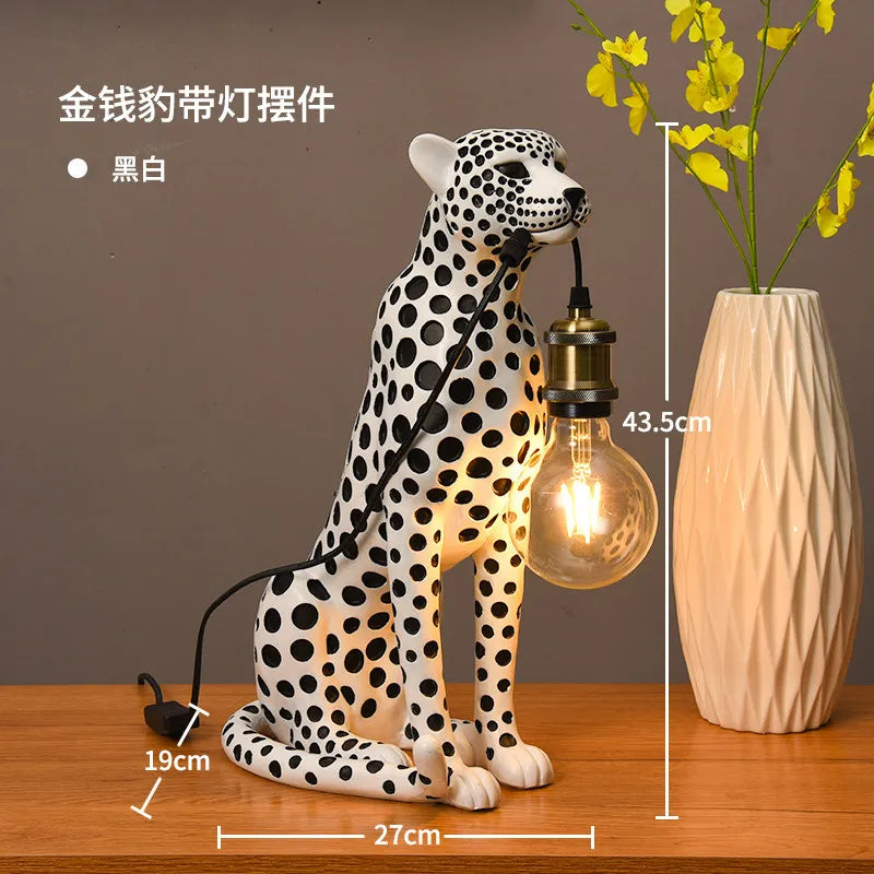 White Spotted Cheetah Premium Lamp with black spots, a lit hanging bulb and 43.5 x 27 x 19 cm dimensions beside a vase.