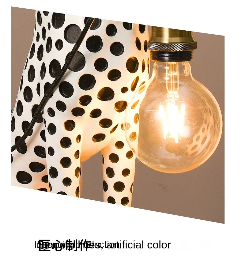 Close-up of the Spotted Cheetah Premium Lamp glowing globe bulb, gold-tone holder and white body with black spots.