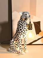 White Spotted Cheetah Premium Lamp holding a glowing bulb by the cord in front of a black-and-white abstract print.