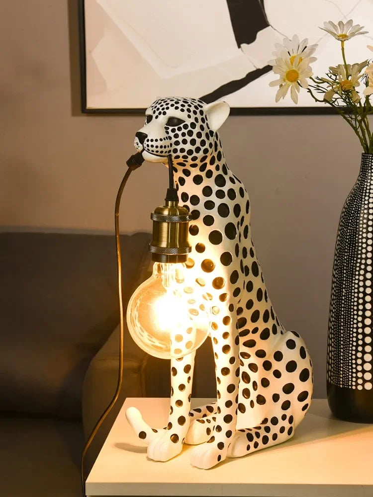 White Spotted Cheetah Premium Lamp in left-facing view with a glowing bulb beside a black patterned vase of daisies.