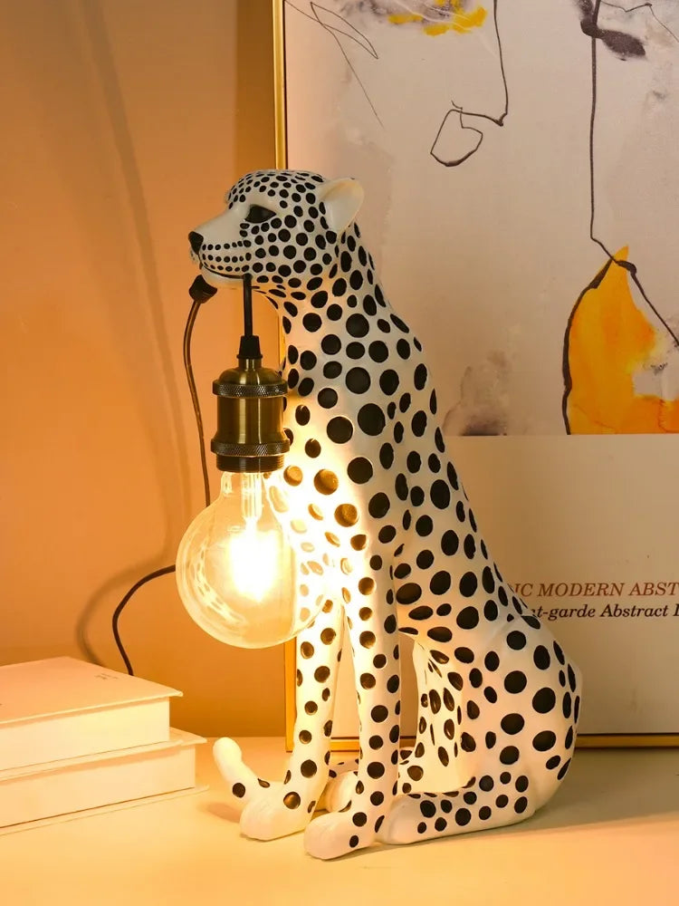 White Spotted Cheetah Premium Lamp in left-facing profile with a glowing hanging bulb, curled tail and books nearby.