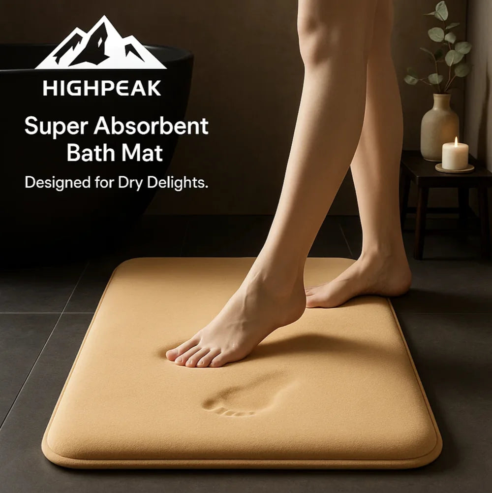 HighPeak Super Absorbent Bath Mat in tan with anti-slip backing, soft texture, shown with bare feet in dark bathroom setting