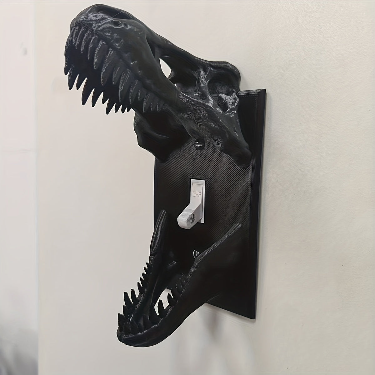Black T-Rex Skull Switch Cover showing raised skull and lower jaw around a toggle switch
