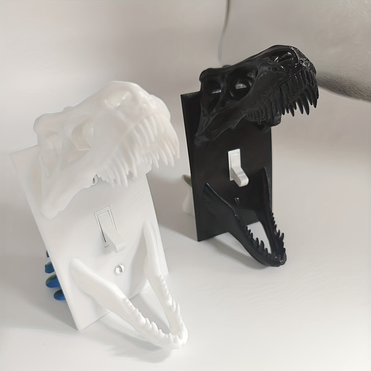 White and black T-Rex Skull Switch Covers displayed side by side