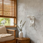 White T-Rex Skull Switch Cover styled on a living room wall beside a window and chair