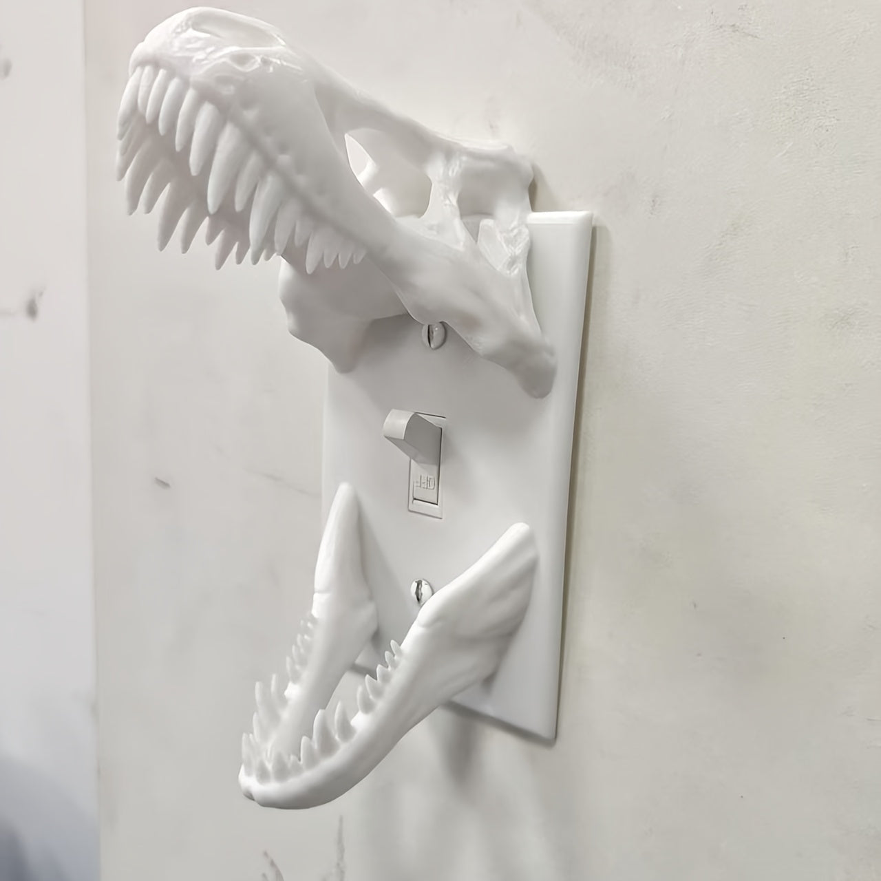 White T-Rex Skull Switch Cover mounted around a toggle light switch, angled side view
