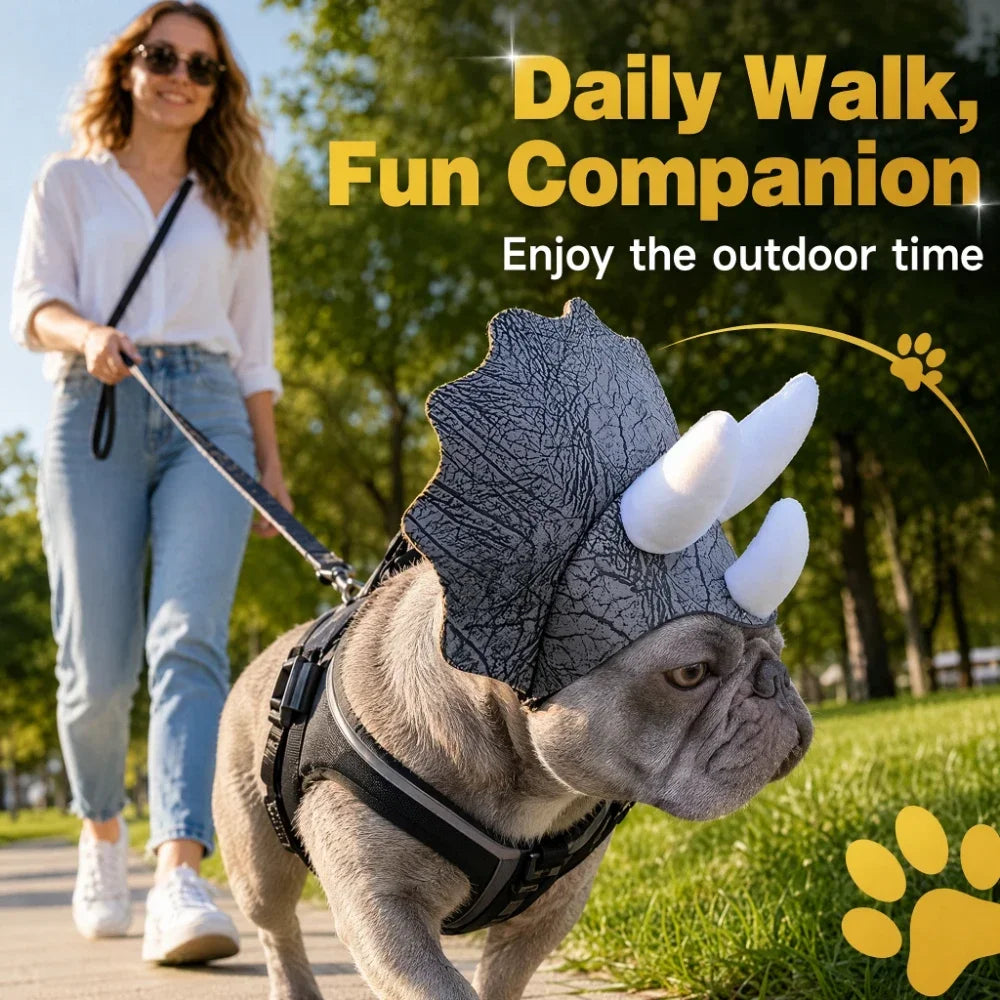 French Bulldog in a dinosaur costume headpiece on a sunny walk with its owner in the background