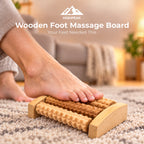 A wooden foot massage board with textured rollers being used on a person's foot on a patterned rug in a cozy living room setting. The HighPeak brand logo and text are displayed at the top.