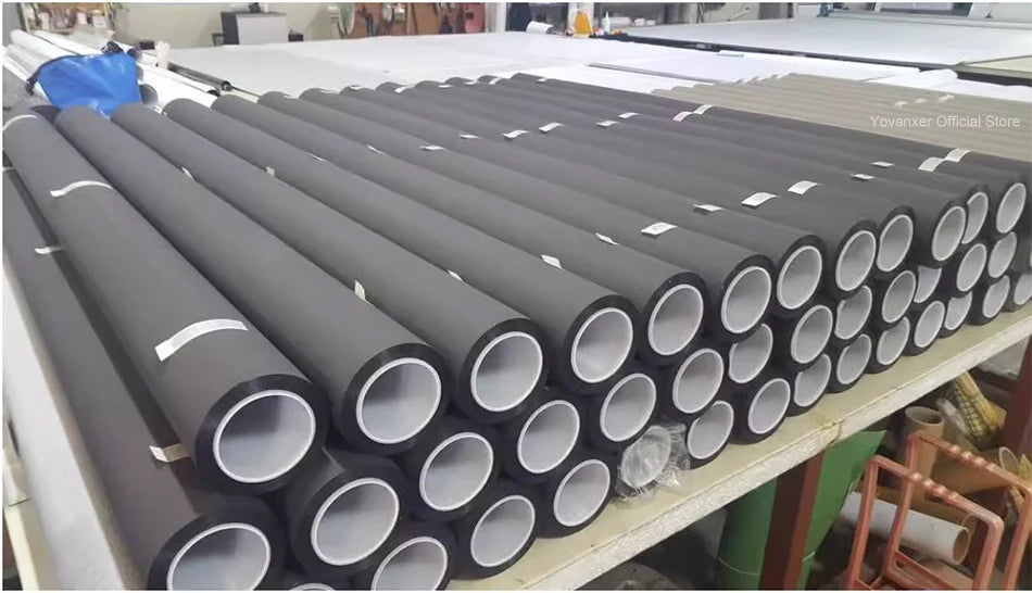 Holographic Window Projection Film supplier workshop table stacked with dark film rolls.