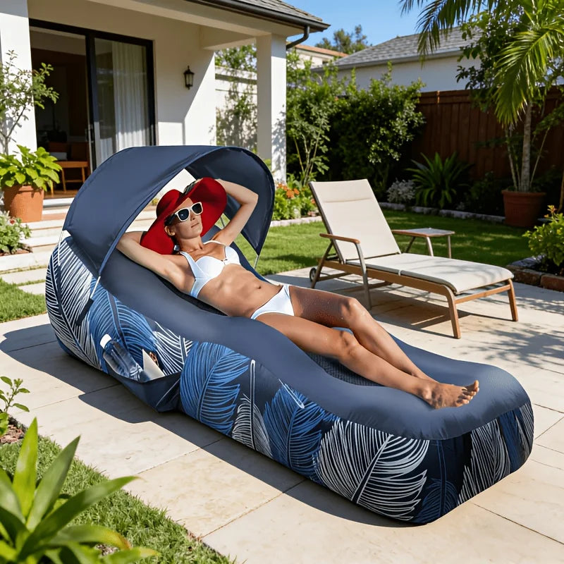 Inflatable Canopy Lounger in navy blue with a woman reclining under its canopy on a garden patio.