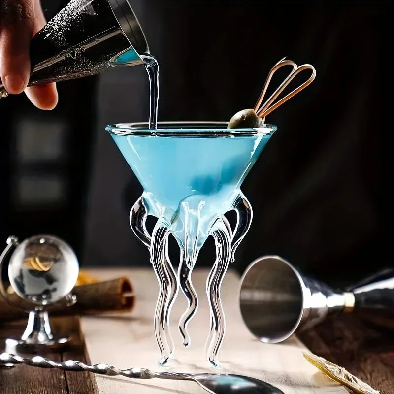 Jellyfish Cocktail Glass with a blue cocktail and olive garnish, showing the clear tentacles during pouring.