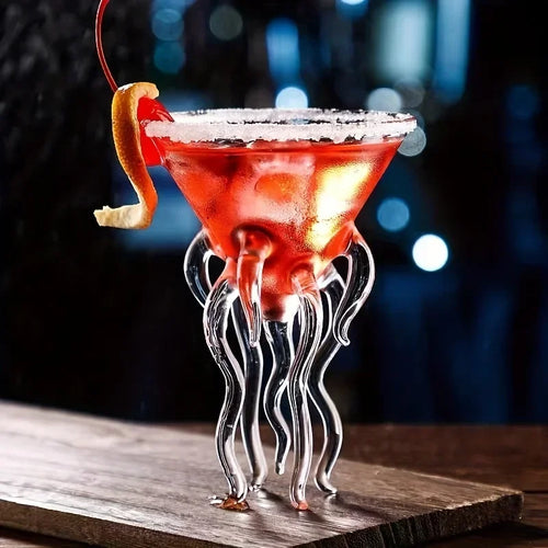 Jellyfish Cocktail Glass holding a red cocktail with a coated rim and citrus peel on a wooden bar.