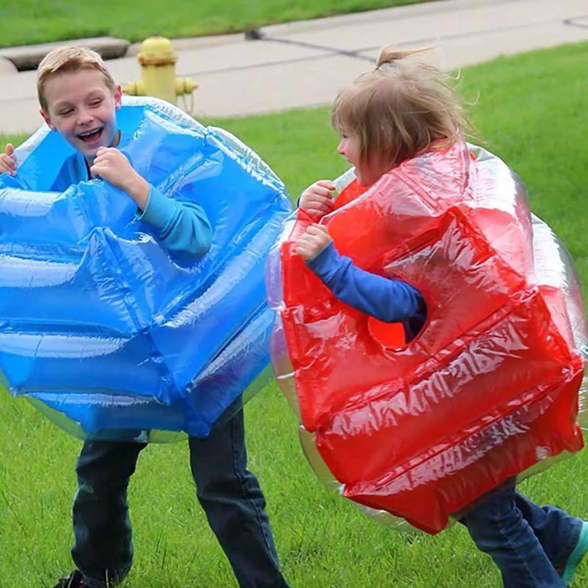 Kids Inflatable Bumper Ball in red and blue worn by two laughing children playing together on a lawn.