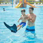 Kids Mermaid Swim Fin worn by a child held by an adult in a swimming pool, with the black blade above water.