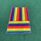 Kids Rainbow Pull Game Mat laid flat on green flooring, showing rainbow stripes and the folded foot pocket