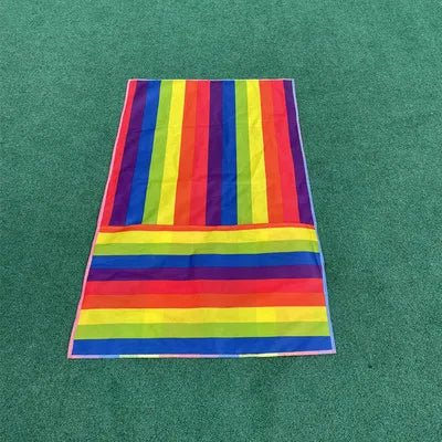 Kids Rainbow Pull Game Mat laid flat on green flooring, showing rainbow stripes and the folded foot pocket