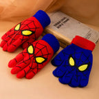Two red kids spider web gloves and one blue glove displayed beside a book.