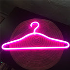 LED Glowing Clothes Hanger in bright pink, shown flat on a round woven mat with its illuminated hook