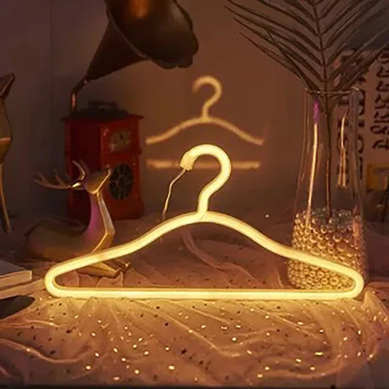 LED Glowing Clothes Hanger in warm white displayed on sheer fabric beside a vase and vintage telephone