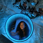 Ice-blue LED Infinity Tunnel Mirror reflecting a curly-haired woman taking a selfie, with roses beside it.