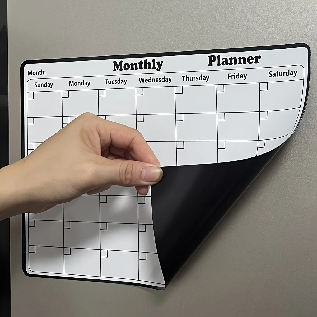 Magnetic Fridge Calendar lifted at the corner to show its flexible black magnetic backing.