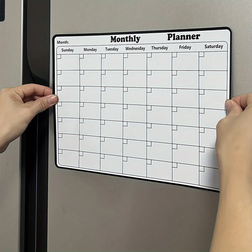 Magnetic Fridge Calendar with a white monthly grid being positioned on a silver refrigerator door.
