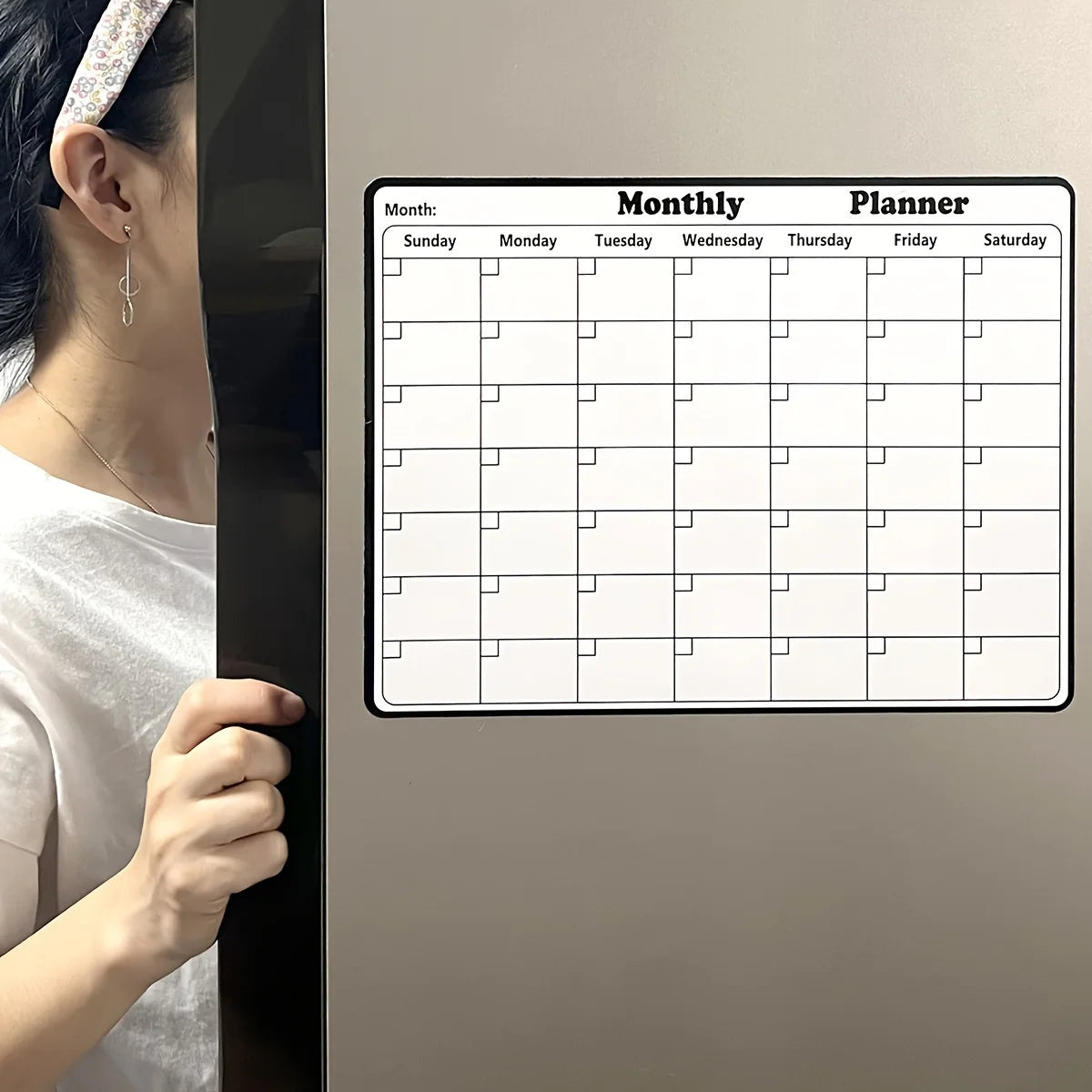 Magnetic Fridge Calendar on a silver refrigerator door being opened by a woman in a white shirt.