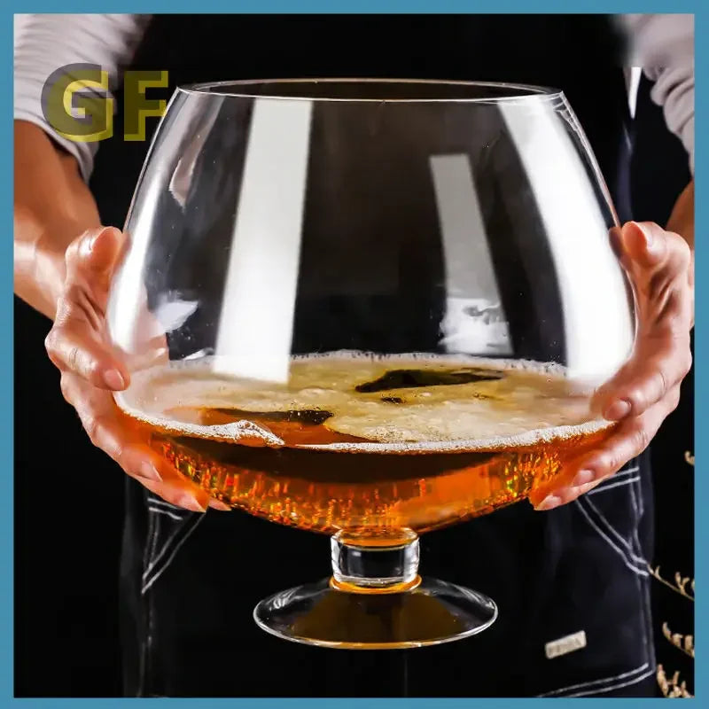 Mega Sized Wine Glass held with two hands in front of a person to show its large bowl and short stem.
