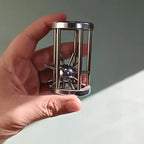 Metal Cage Challenge held upright in one hand to show its compact cylindrical shape and silver finish