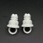 Mini Birthday Cake Ring in white shown as two examples side by side on a dark textured surface.
