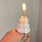 Mini Birthday Cake Ring in white worn on a finger, showing the cake tiers, bow and candle in close-up.