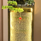 Moonlit Bonsai Waterfall water curtain framed by warm light with a red hanging ornament and green foliage.