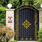 No Trespassing Security Sign displayed on a stone pillar beside an ornate black and gold entrance gate.