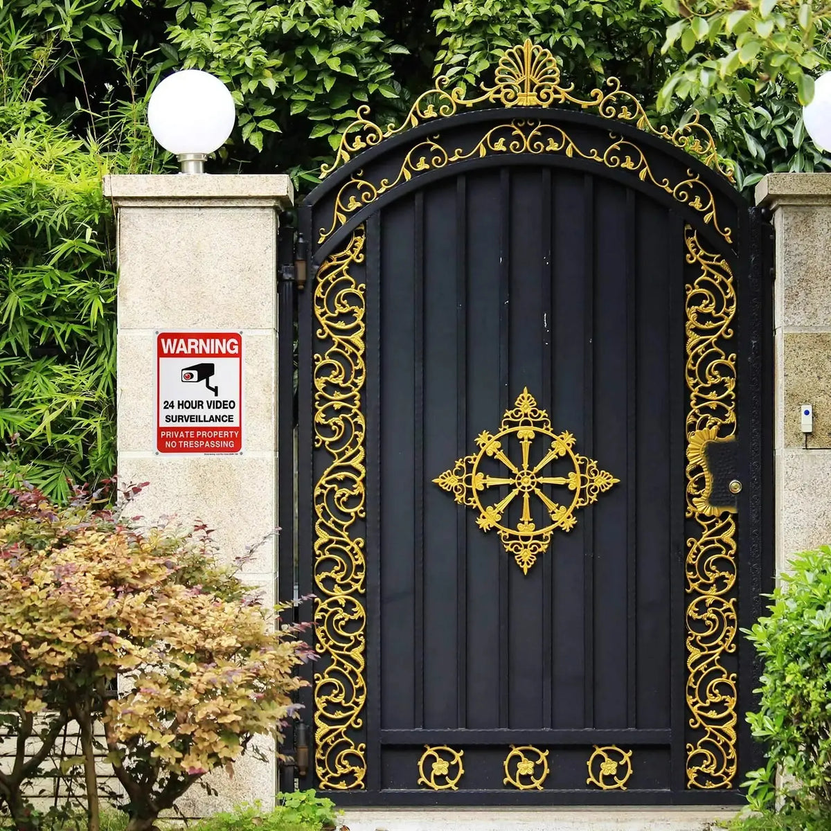 No Trespassing Security Sign displayed on a stone pillar beside an ornate black and gold entrance gate.