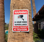 No Trespassing Security Sign attached to a palm tree near a property with a pool.