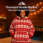 HighPeak Oversized Hoodie Blanket in red and white with reindeer pattern worn by smiling woman near cozy fireplace
