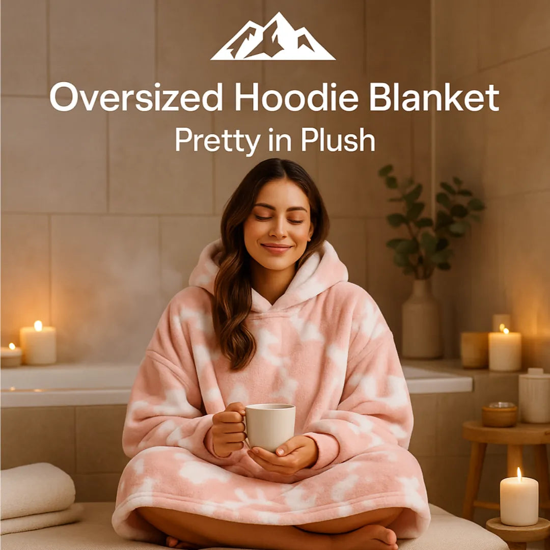 HighPeak Oversized Hoodie Blanket in pink plush worn by a woman holding a mug in a cozy candlelit room