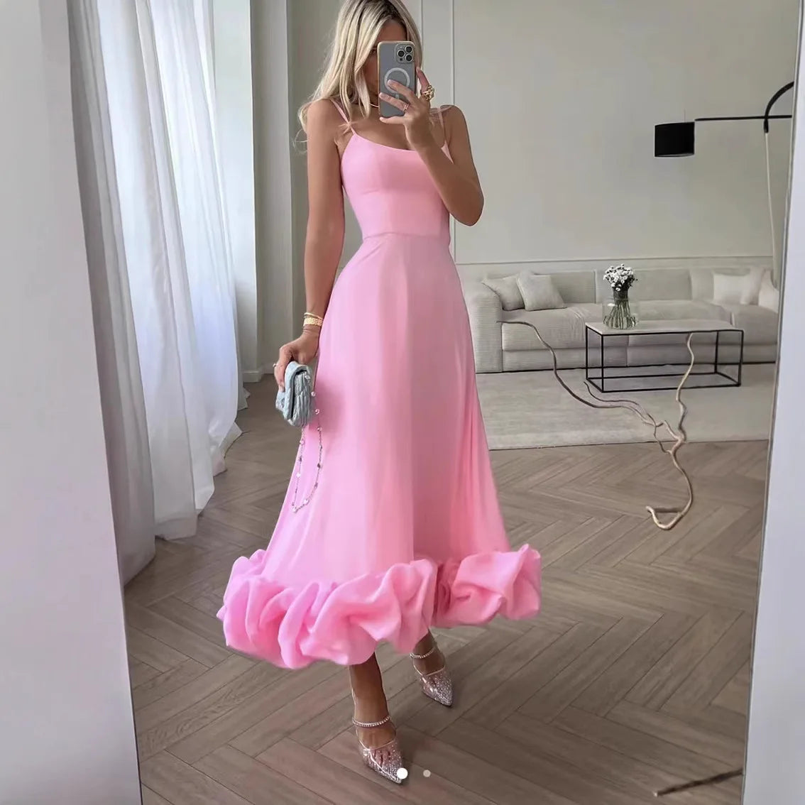 Pink spaghetti-strap Petal Waltz Ruffle Dress shown in a living room mirror