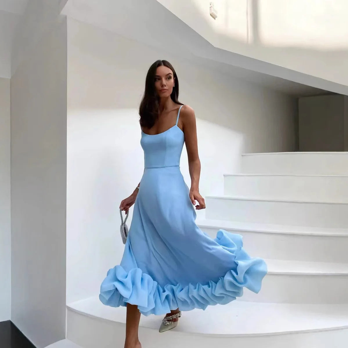 Sky blue Petal Waltz Ruffle Dress with a billowing ruffled hem, worn on stairs