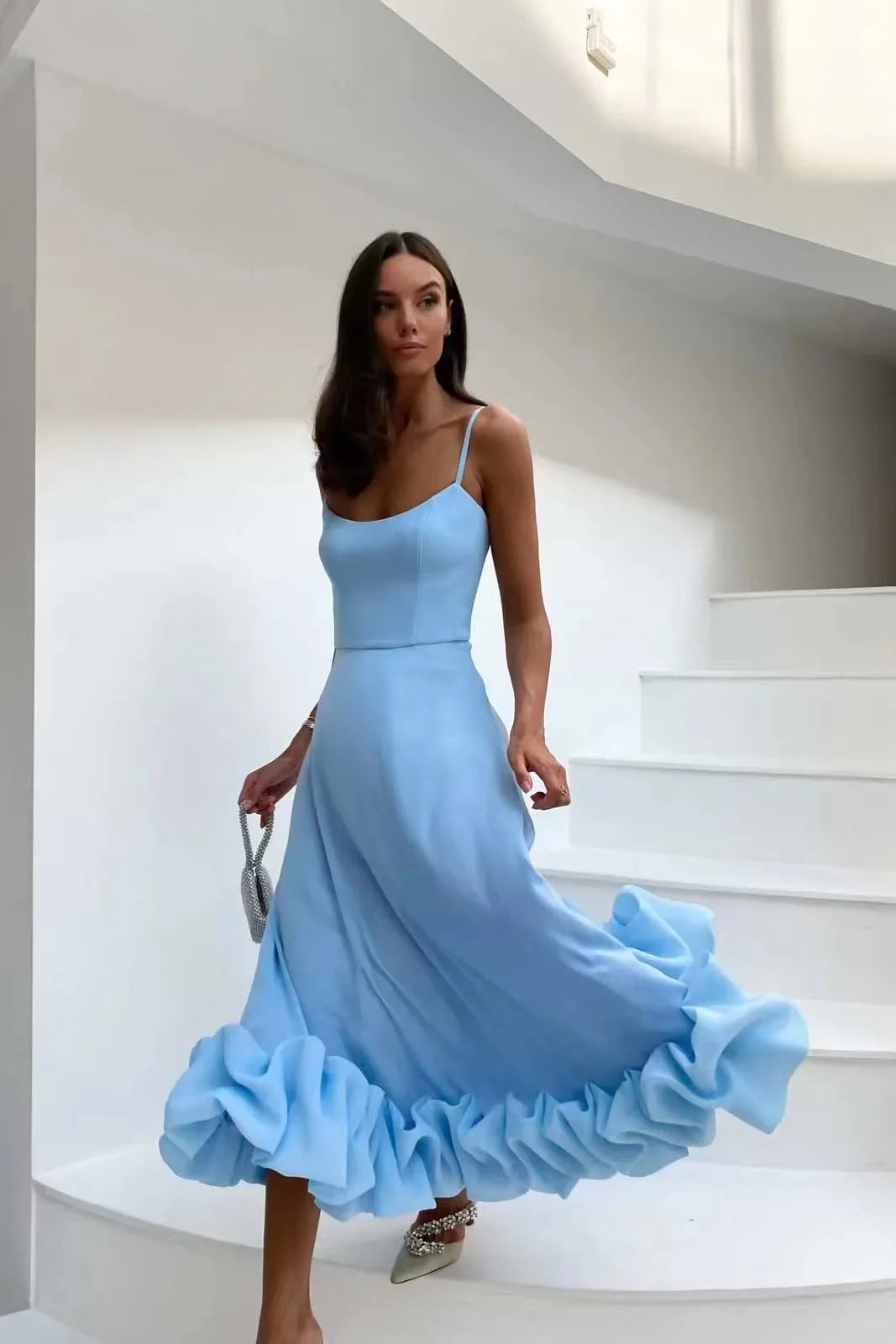 Sky blue Petal Waltz Ruffle Dress with flowing A-line skirt on a white staircase