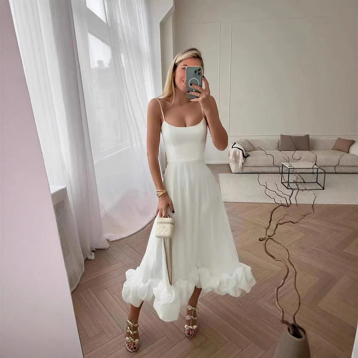 White Petal Waltz Ruffle Dress in a living room mirror with its sculpted ruffle hem