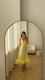 Full-length yellow ruffle dress with spaghetti straps in an arched mirror; gallery style reference