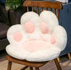 Plush Cat Paw Cushion in white with pink paw pads displayed on a wooden chair