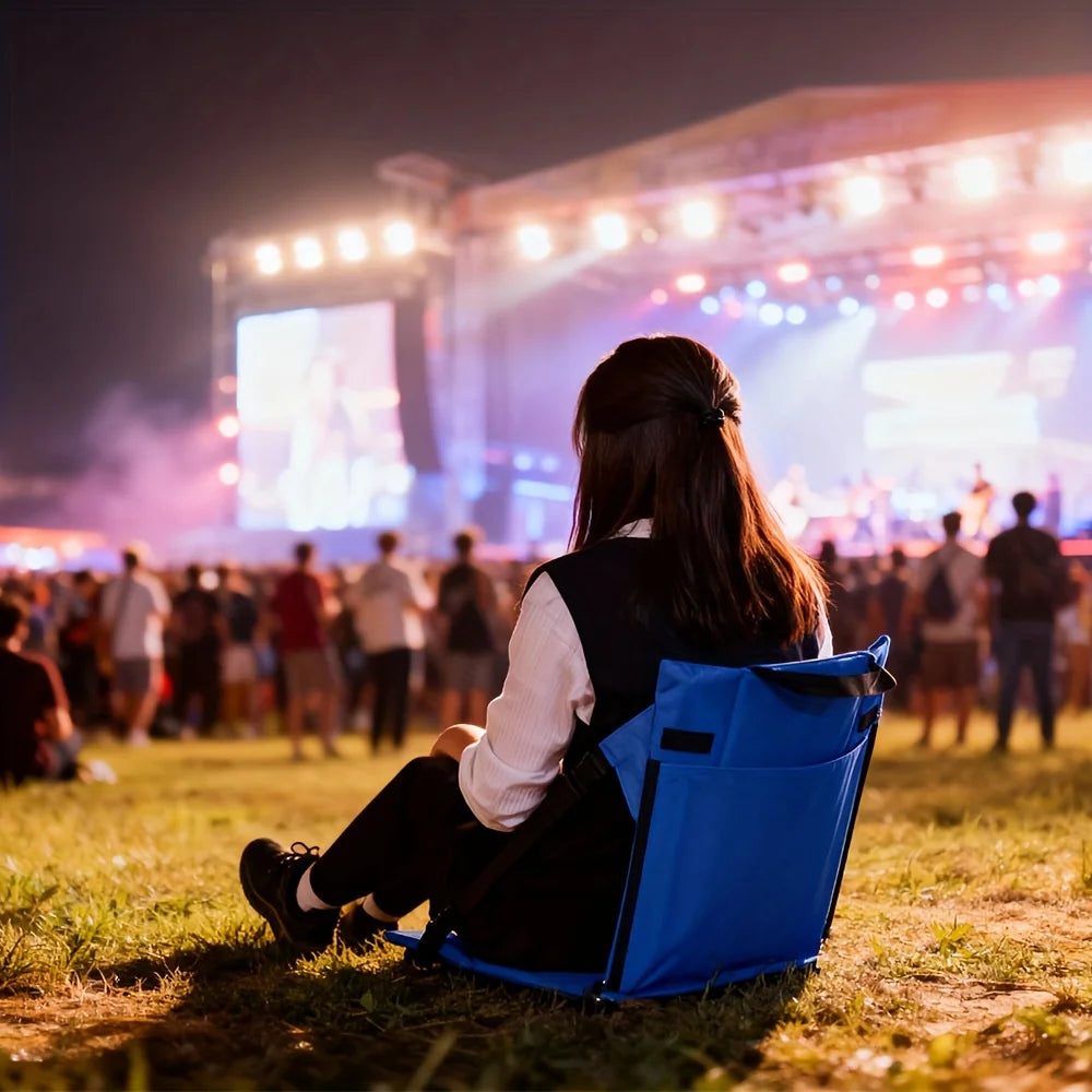 Portable Bleacher Seat in blue used on grass by a spectator watching an outdoor concert at night