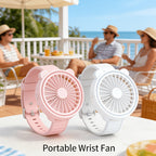 Portable Mini Wrist Fan pink and white pair displayed on a seaside patio table
