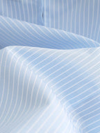 Portofino Ruffle Top close-up showing the light blue and white polyester woven stripe pattern