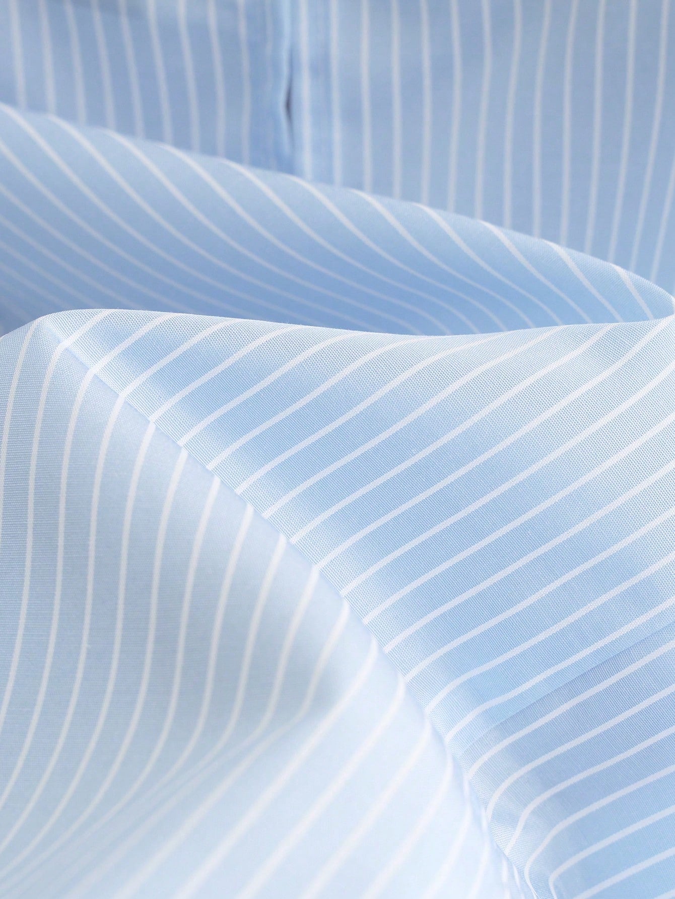Portofino Ruffle Top close-up showing the light blue and white polyester woven stripe pattern