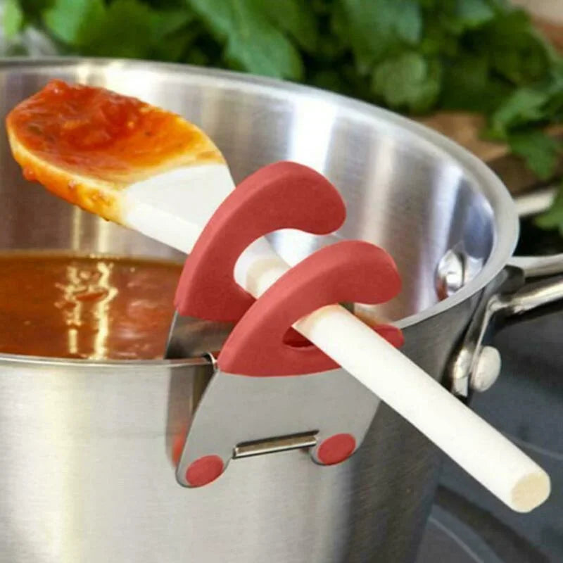 Red pot clip holding a sauce-covered white spatula above a stainless steel pot
